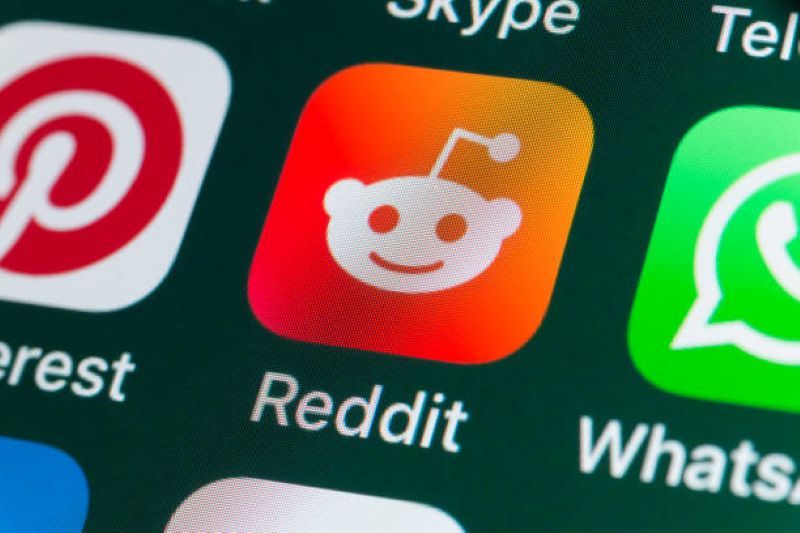 Close-up of the Reddit app icon on a smartphone screen, surrounded by other social media app icons.