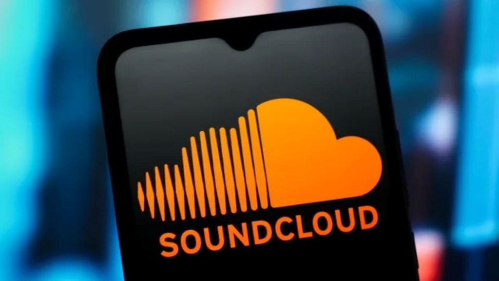 A smartphone showing the SoundCloud logo with an orange cloud and waveform icon against a dark, blurred background.
