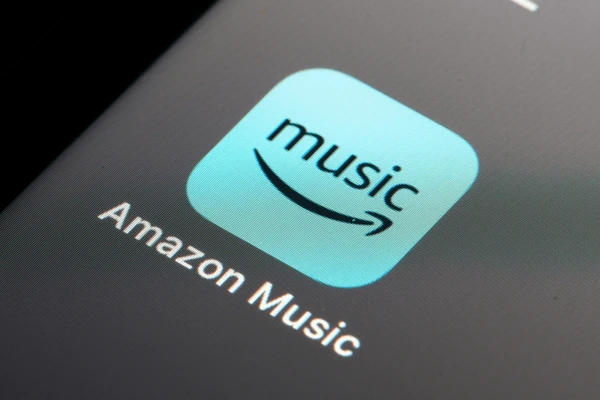 A close-up of a smartphone screen showing the Amazon Music app icon with a blue background and curved arrow smile.