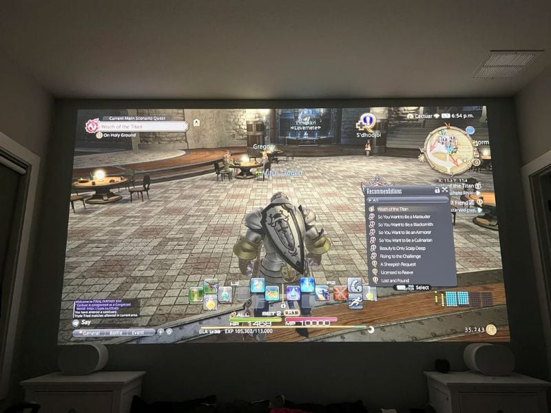 Bedroom gaming setup with a video game projected onto a large blank wall above the bed.