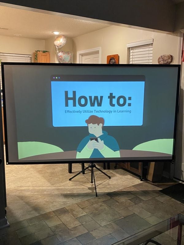 Large portable projector screen stand displaying a how-to presentation in an indoor living space.