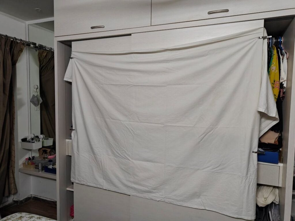 White bed sheet stretched across an open closet to create a budget projector screen.