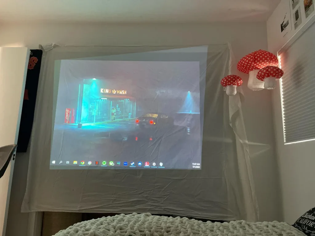 Movie projected onto a wrinkled white bed sheet hung on a bedroom wall.