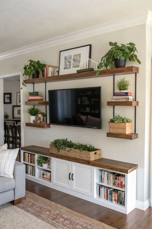 Built-in TV wall with floating wood shelves, books, framed art, baskets, and plants arranged around a mounted television.