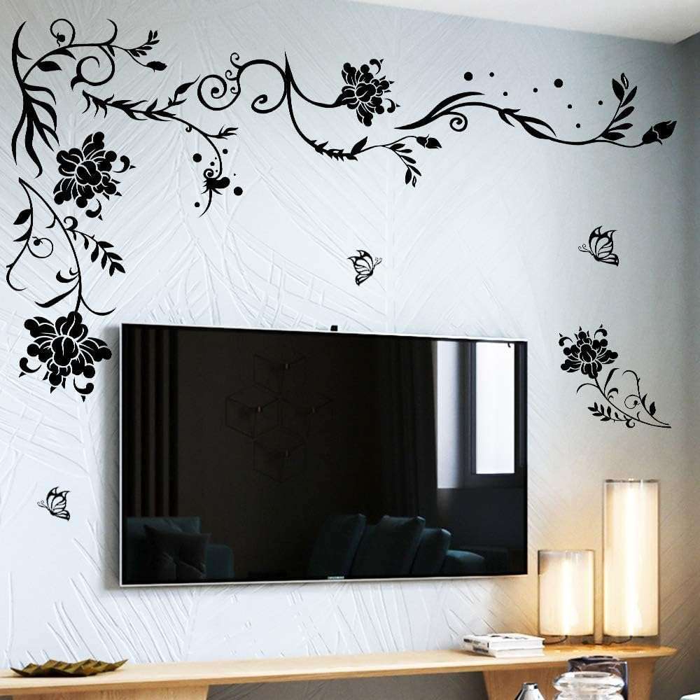 Wall-mounted TV surrounded by black floral vine and butterfly wall decals on a light-colored wall.