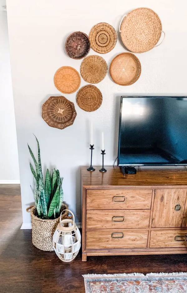 TV console with woven basket wall decor arranged above and beside the television for a warm boho-style living room look.