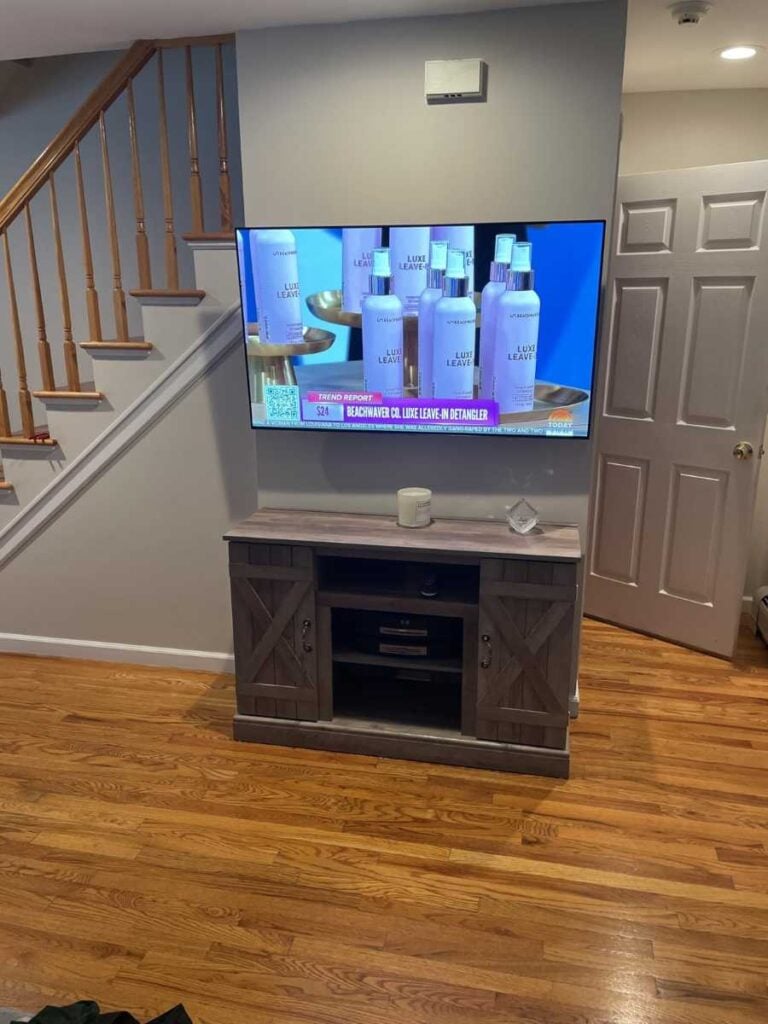 Wall-mounted TV above a rustic media cabinet with cords hidden inside the wall.