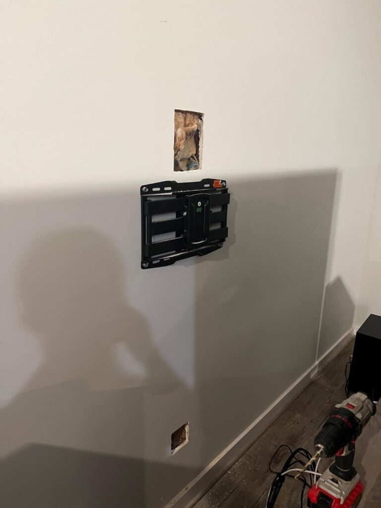In-progress TV wall mount installation with wall openings cut for an in-wall cable management kit.