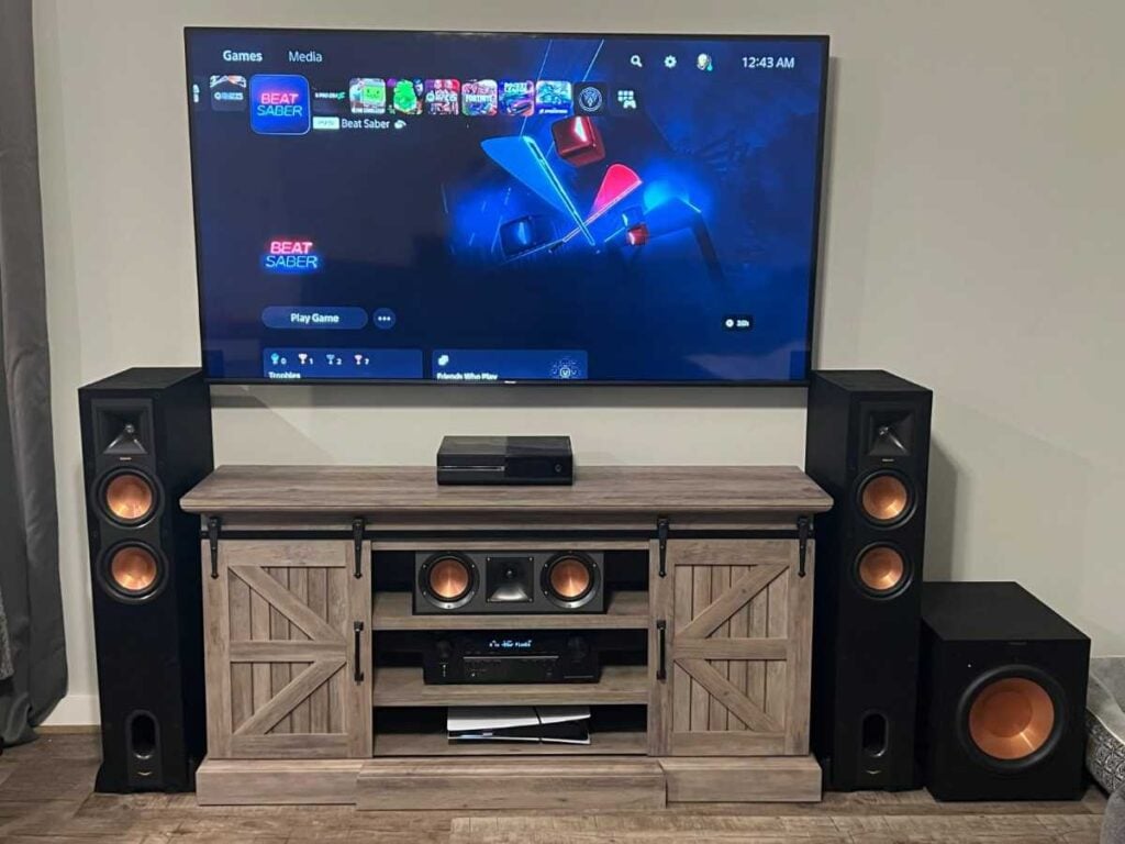 Wall-mounted TV and home theater setup with speakers, subwoofer, media console, and hidden cables.
