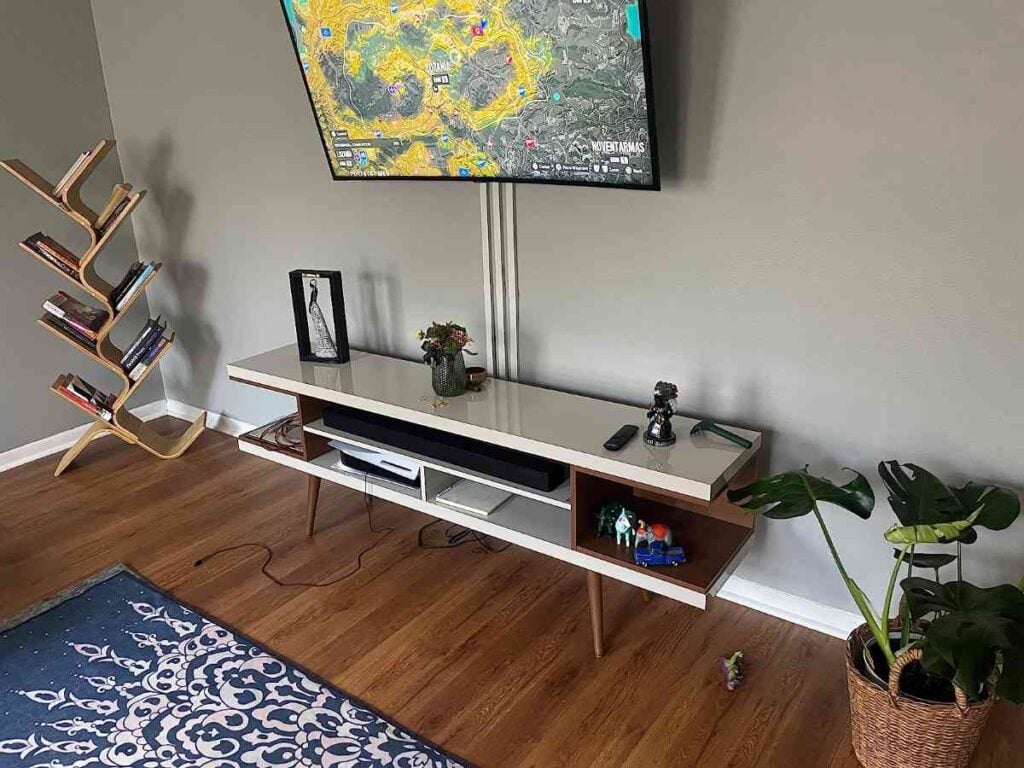Wall-mounted TV with white cord covers neatly hiding cables down the wall behind a media console.