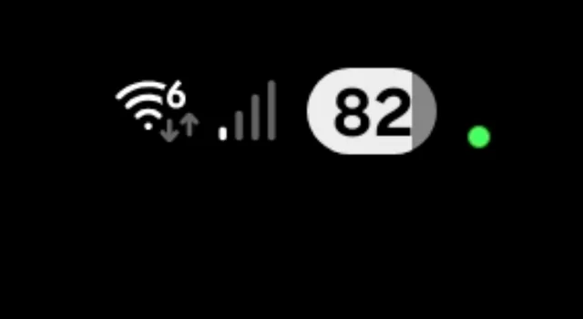 A close-up of an Android phone status bar shows Wi-Fi, signal, battery percentage, and a small green privacy dot on a black background.