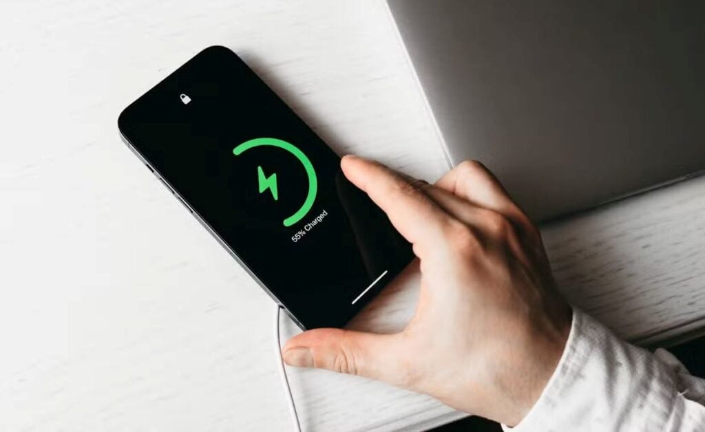 iPhone charging on table with green battery icon display showing partial charge