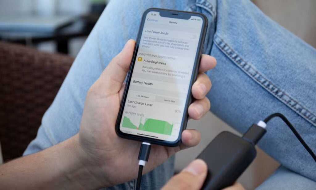 iPhone charging on table with green battery icon display showing partial charge