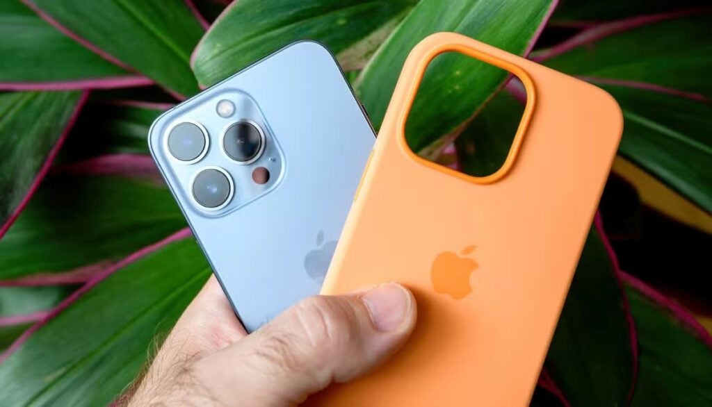 iPhone with orange protective case being held next to the device without case showing camera lenses