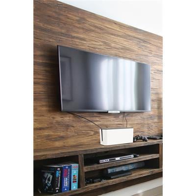 Wall-mounted TV above a wooden media console with a small white cable management box hiding cords beneath the screen.