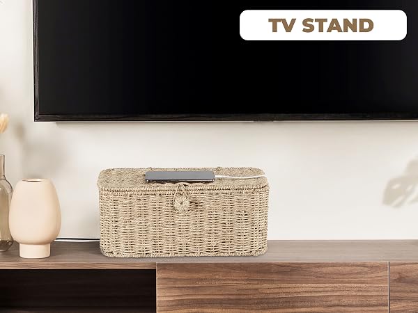 Woven basket-style cable management box on a TV stand hides cords below a wall-mounted television.